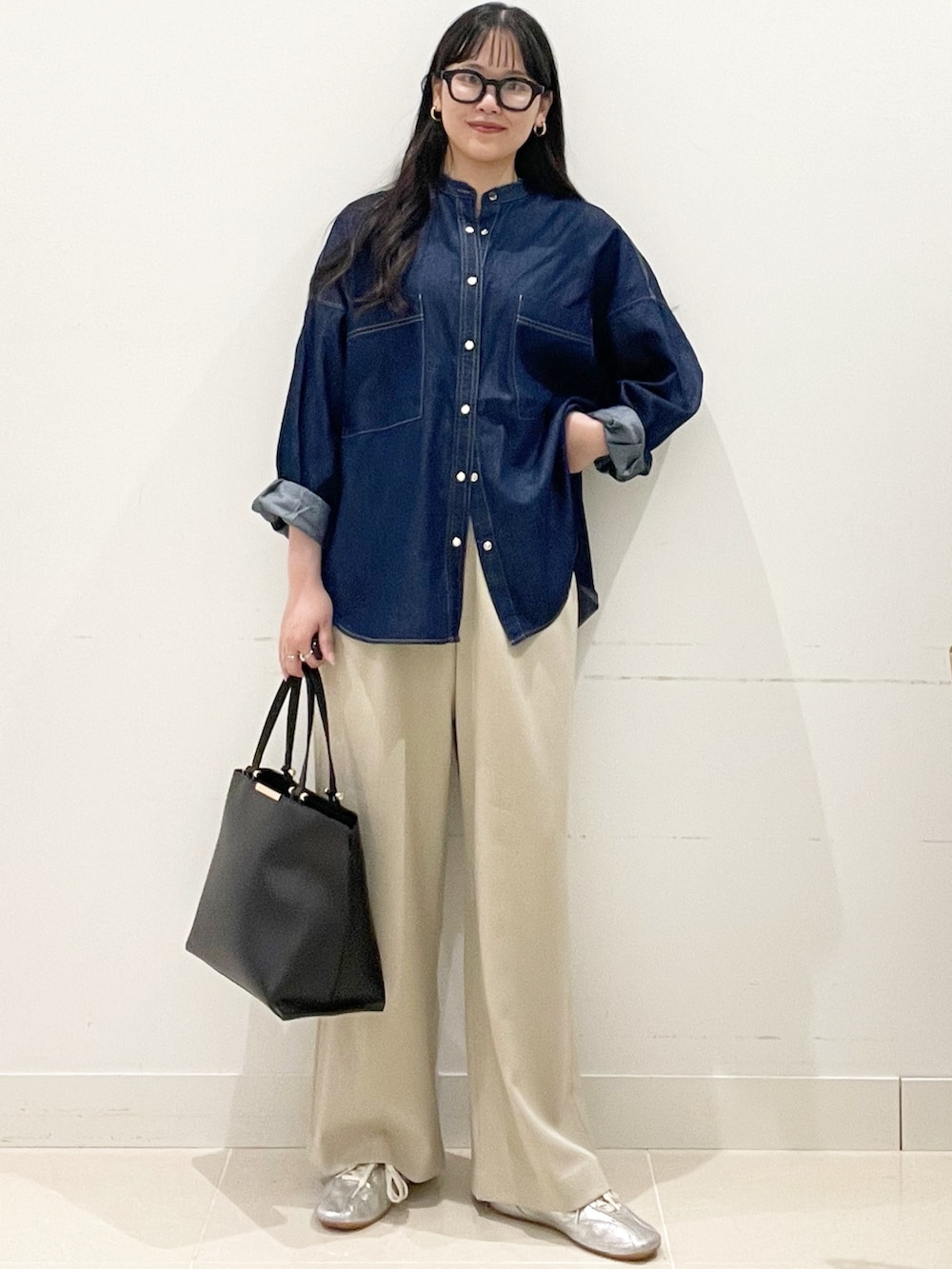 ベージュ系のスラックス、ブラック系のトートバッグ、ブルー系のシャツ/ブラウスを着用したレディースの春コーディネートの2枚目の写真