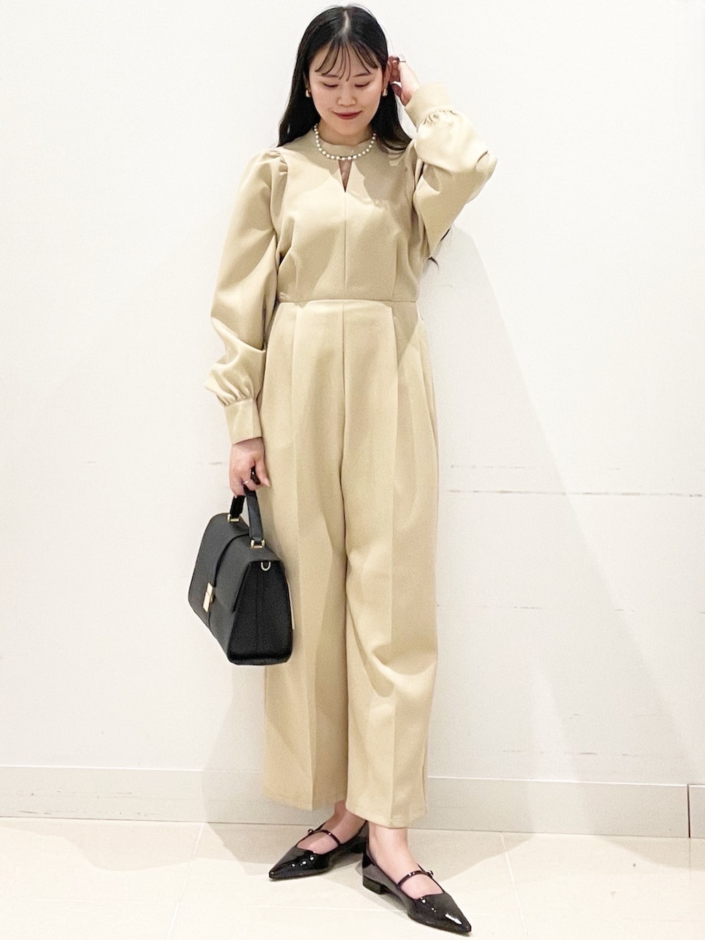 ブラック系のパンプス、ベージュ系のつなぎ/オールインワン、ブラック系のハンドバッグを着用したレディースの冬コーディネートの2枚目の写真