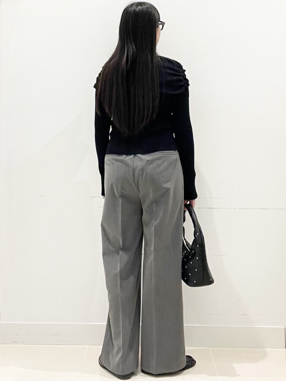 グレー系のスラックス、ブラック系のハンドバッグ、ブラック系のニット/セーターを着用したレディースの春コーディネートの5枚目の写真