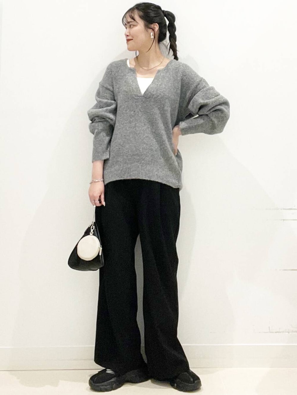 ブラック系のその他パンツ、ブラック系のスニーカー、グレー系のニット/セーターを着用したレディースの春コーディネートの2枚目の写真