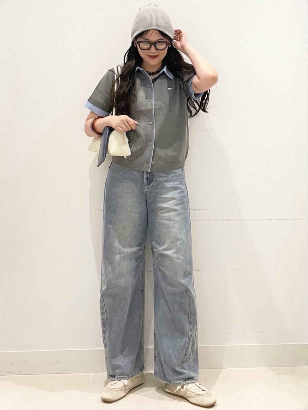 ブルー系のデニムパンツ、グレー系のカーディガン/ボレロ、ホワイト系のショルダーバッグを着用したレディースの春コーディネートの3枚目の写真