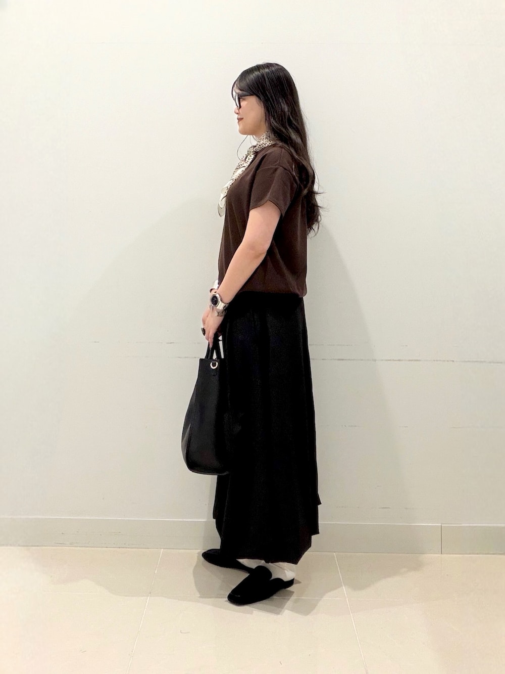 ブラウン系のTシャツ/カットソー、ブラック系のスカート、ブラック系のトートバッグを着用したレディースの秋コーディネートの4枚目の写真