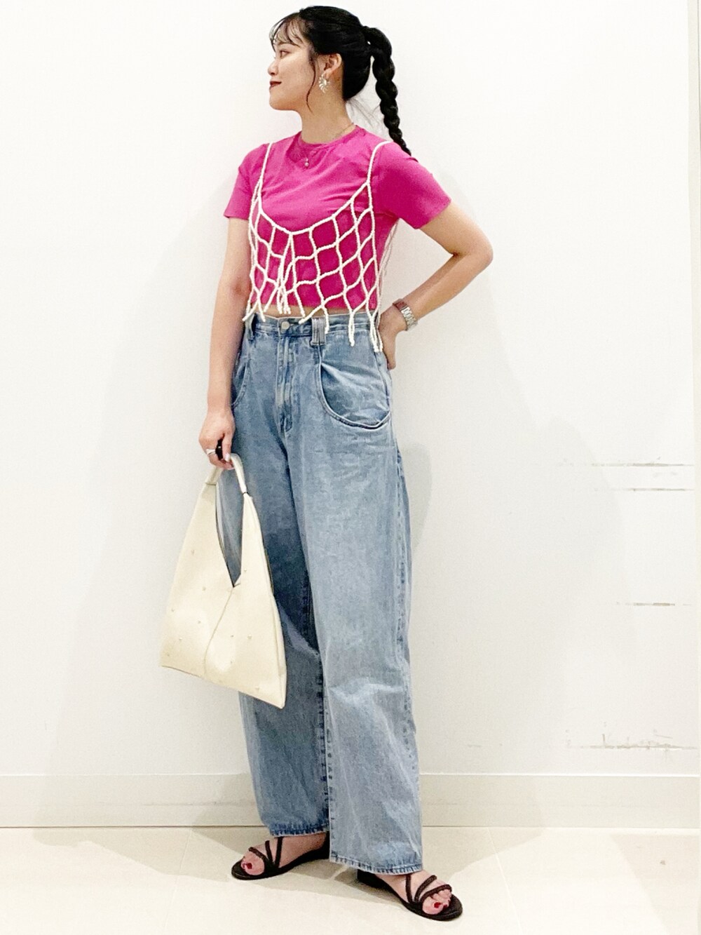 ブルー系のデニムパンツ、ブラック系のサンダル、ホワイト系のトートバッグを着用したレディースの夏コーディネートの2枚目の写真