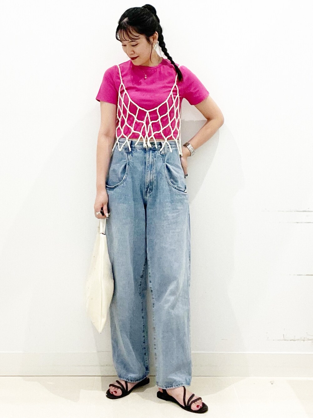 ブルー系のデニムパンツ、ブラック系のサンダル、ホワイト系のトートバッグを着用したレディースの夏コーディネートの5枚目の写真