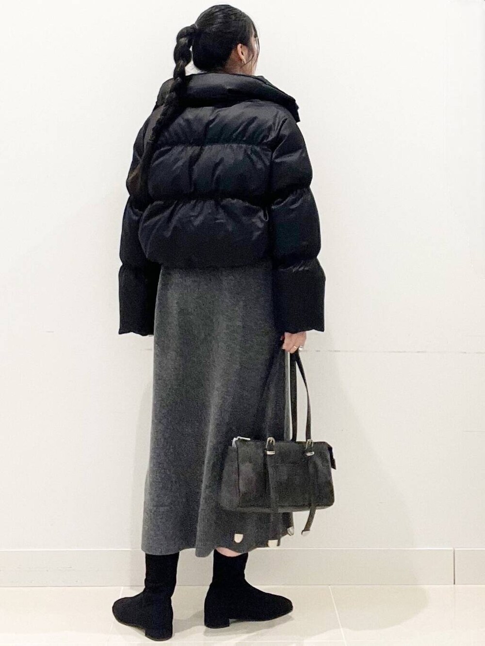 ブラック系のダウンジャケット/コート、ブラック系のブーツ、グレー系のワンピースを着用したレディースの冬コーディネートの6枚目の写真