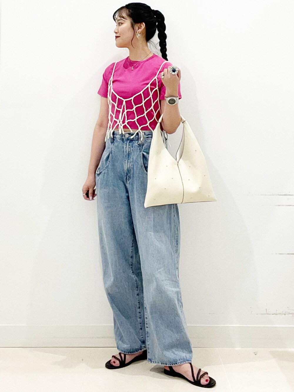 ブルー系のデニムパンツ、ブラック系のサンダル、ホワイト系のトートバッグを着用したレディースの夏コーディネートの4枚目の写真