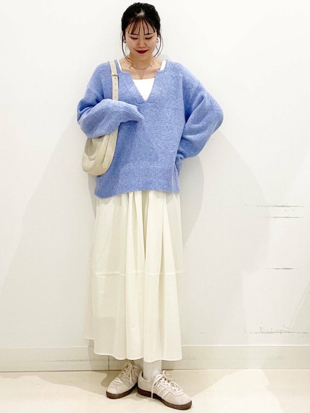 ホワイト系のスニーカー、ブルー系のニット/セーター、ベージュ系のショルダーバッグを着用したレディースの春コーディネートの5枚目の写真
