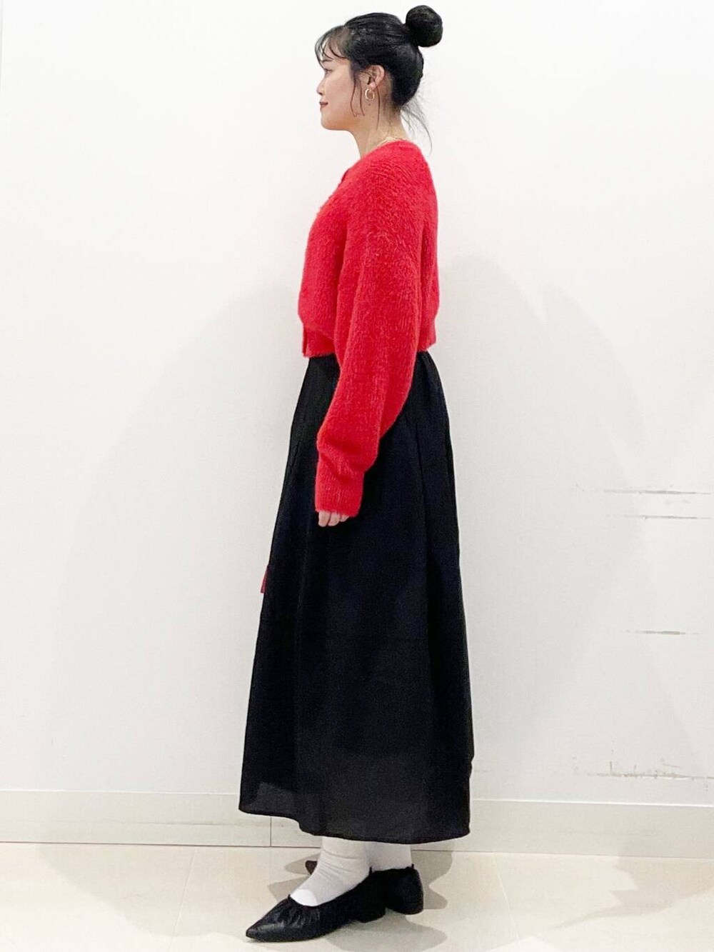 レッド系のボストンバッグ、レッド系のニット/セーター、ブラック系のバレエシューズを着用したレディースの冬コーディネートの6枚目の写真