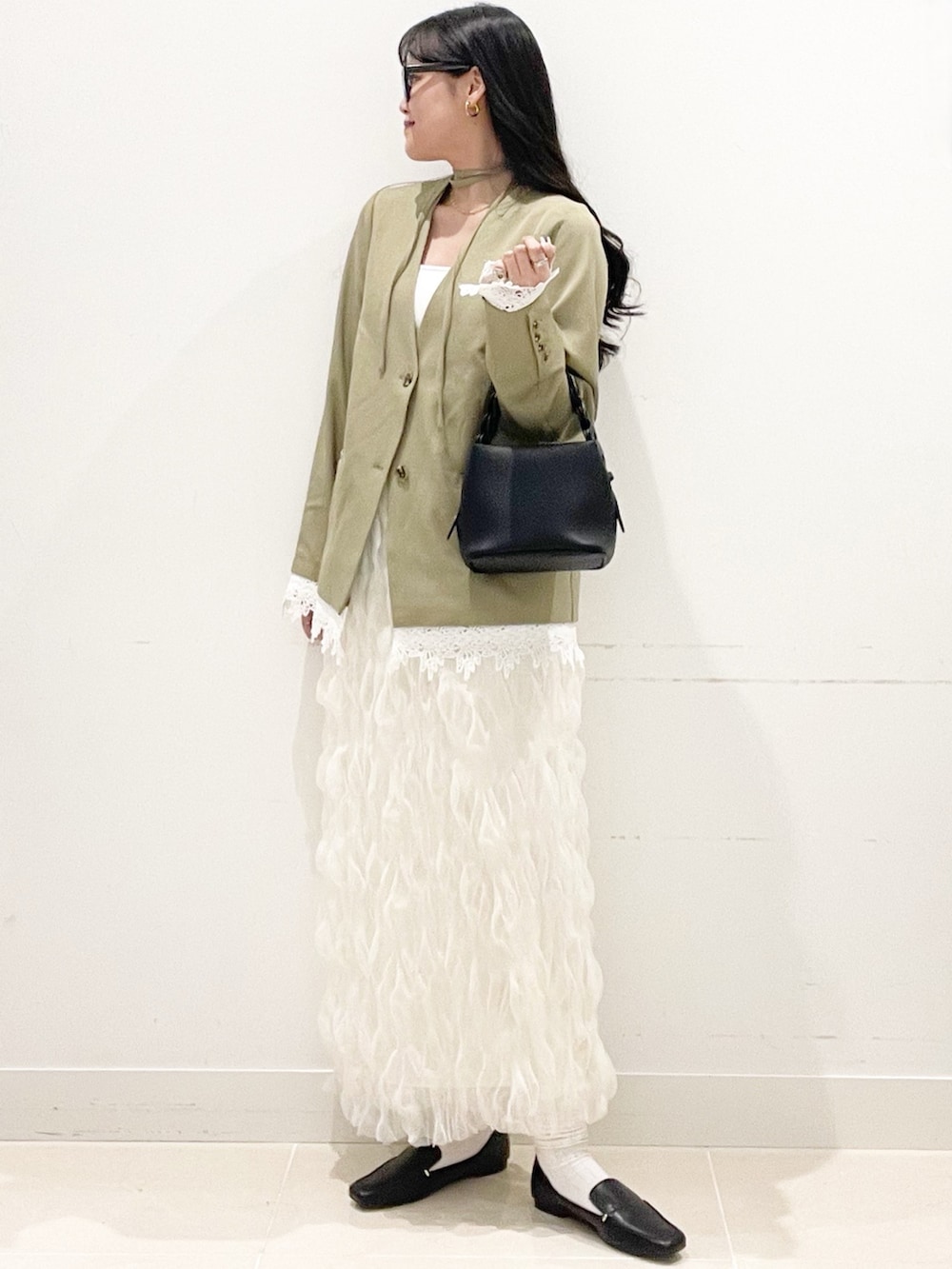 ブラック系のローファー、ホワイト系のスカート、ベージュ系のノーカラージャケットを着用したレディースの春コーディネートの3枚目の写真