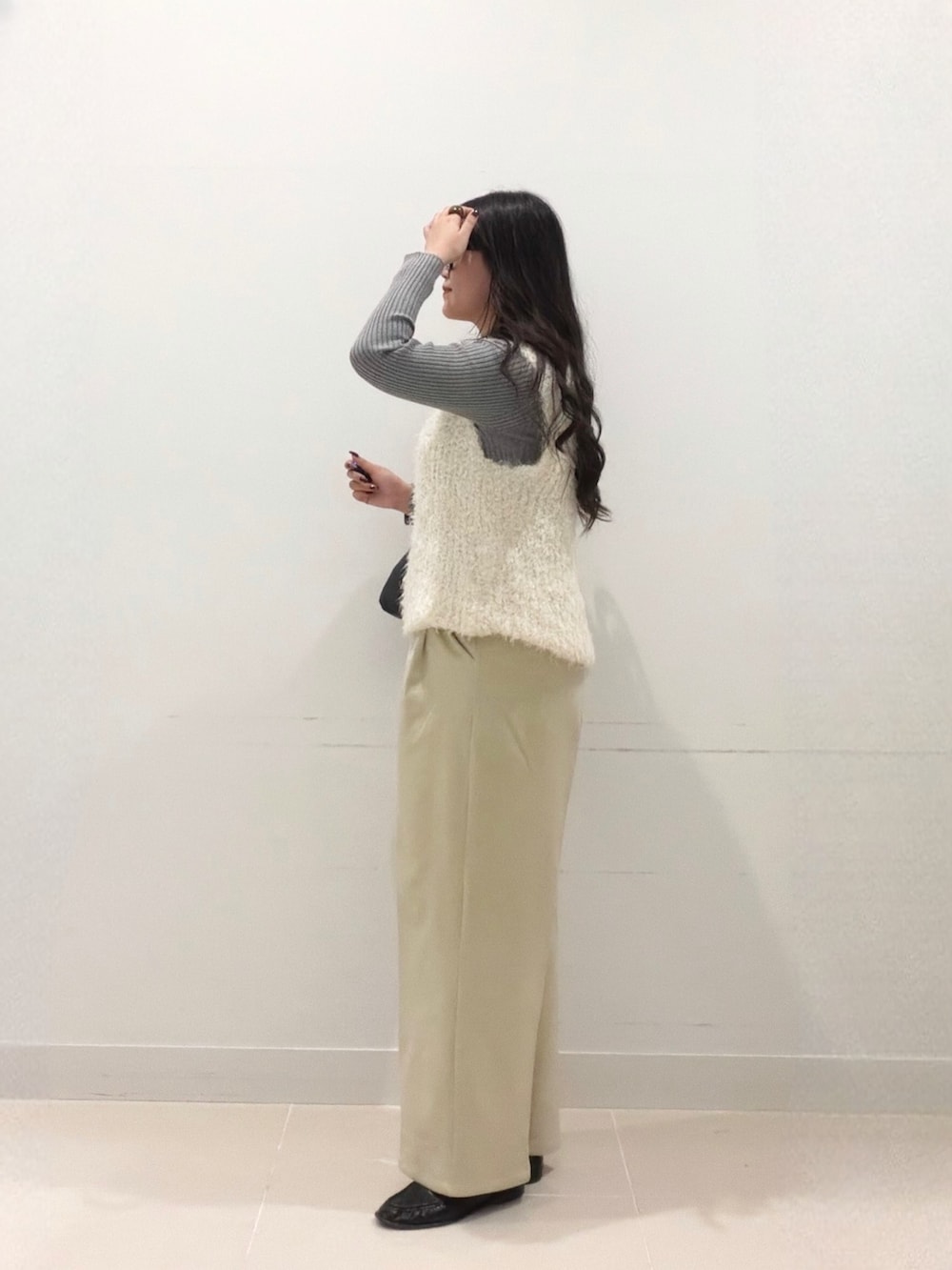 グレー系のニット/セーター、ベージュ系のその他パンツ、ホワイト系のベストを着用したレディースの秋コーディネートの3枚目の写真