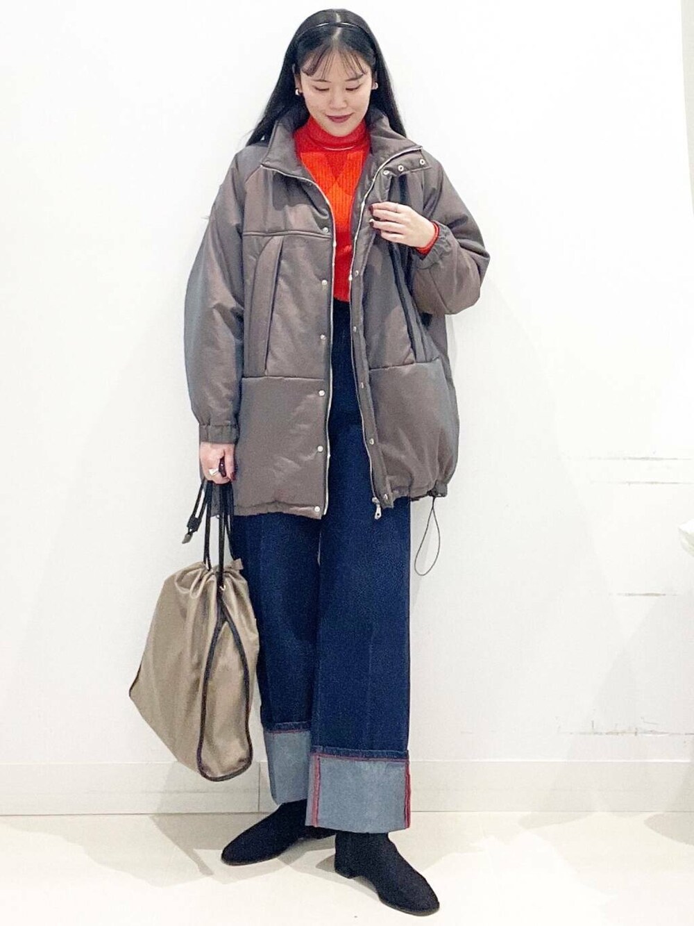 ブラック系のブーツ、レッド系のニット/セーター、ブルー系のデニムパンツを着用したレディースの冬コーディネートの4枚目の写真