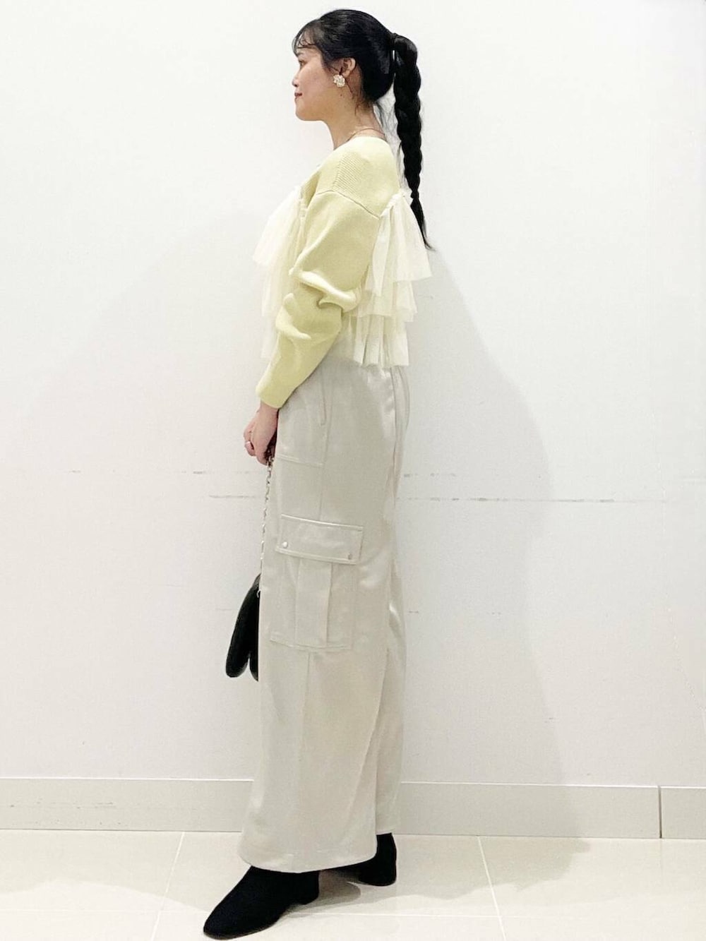 ブラック系のブーツ、ブラック系のショルダーバッグ、イエロー系のニット/セーターを着用したレディースの冬コーディネートの6枚目の写真