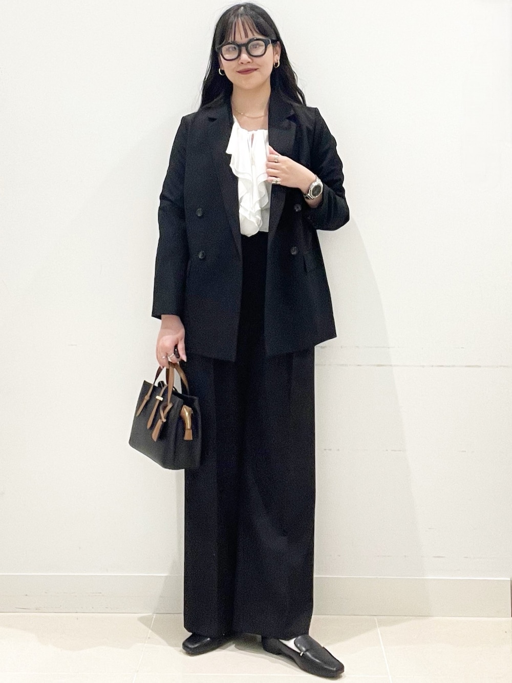 ブラック系のローファー、ブラック系のハンドバッグ、ブラック系のテーラードジャケットを着用したレディースの春コーディネートの2枚目の写真