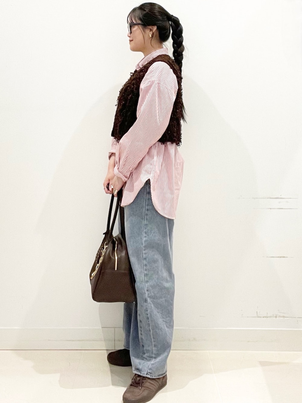 ブラウン系のスニーカー、ブルー系のデニムパンツ、ブラウン系のボストンバッグを着用したレディースの冬コーディネートの5枚目の写真