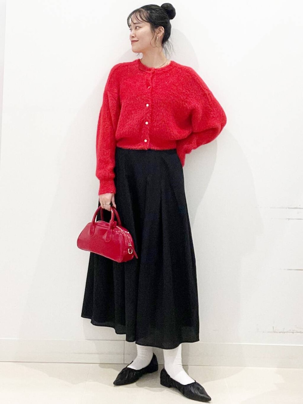 レッド系のボストンバッグ、レッド系のニット/セーター、ブラック系のバレエシューズを着用したレディースの冬コーディネートの2枚目の写真