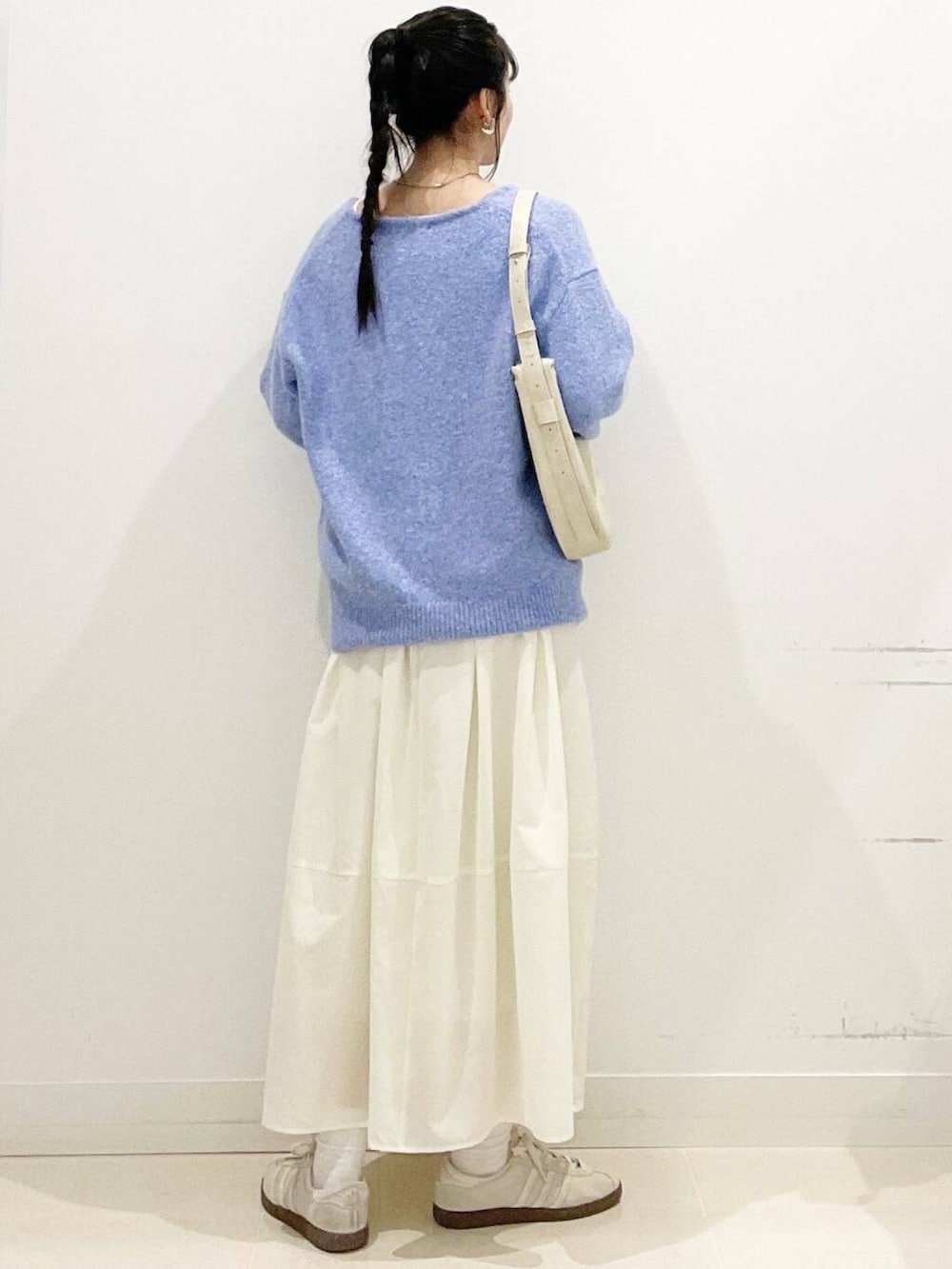 ホワイト系のスニーカー、ブルー系のニット/セーター、ベージュ系のショルダーバッグを着用したレディースの春コーディネートの7枚目の写真