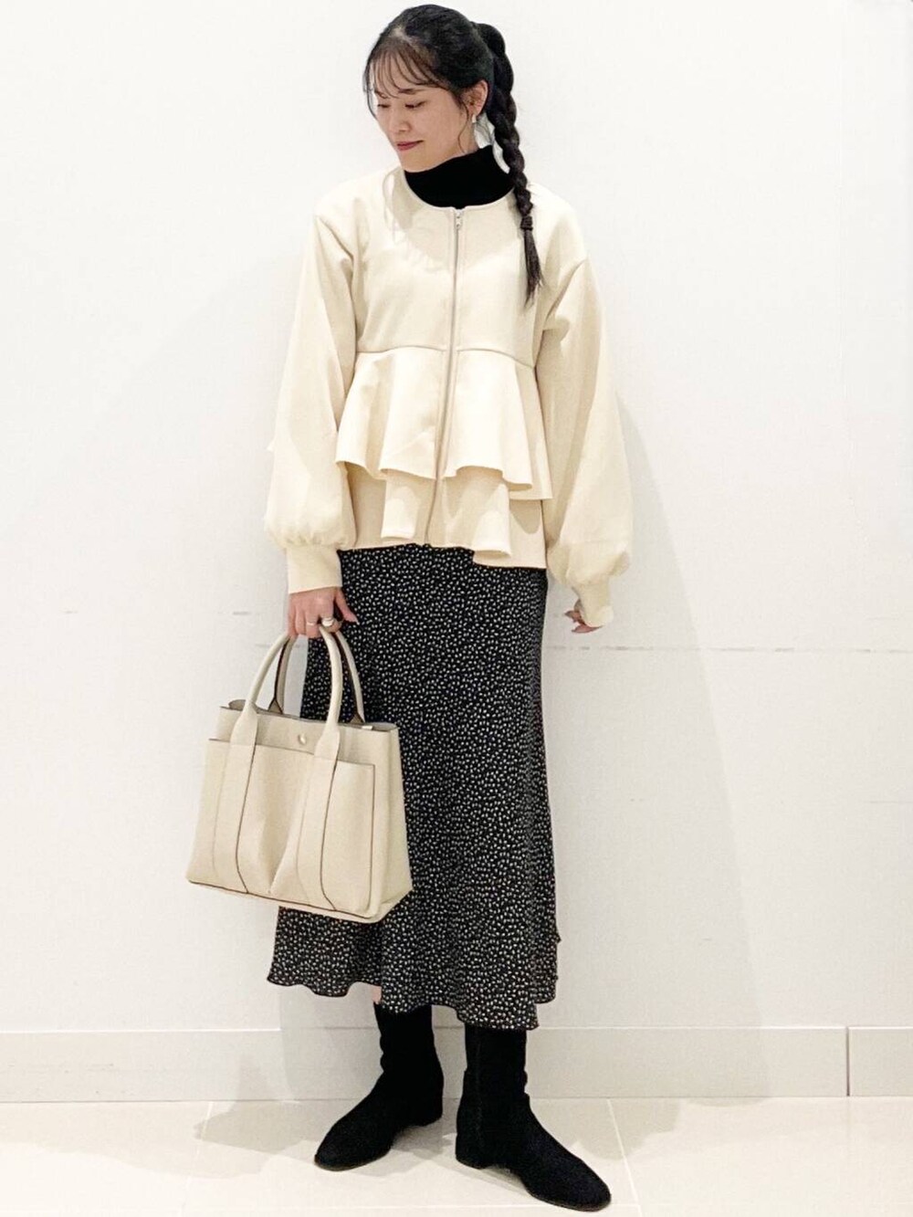ブラック系のニット/セーター、ブラック系のブーツ、ホワイト系のトートバッグを着用したレディースの冬コーディネートの4枚目の写真