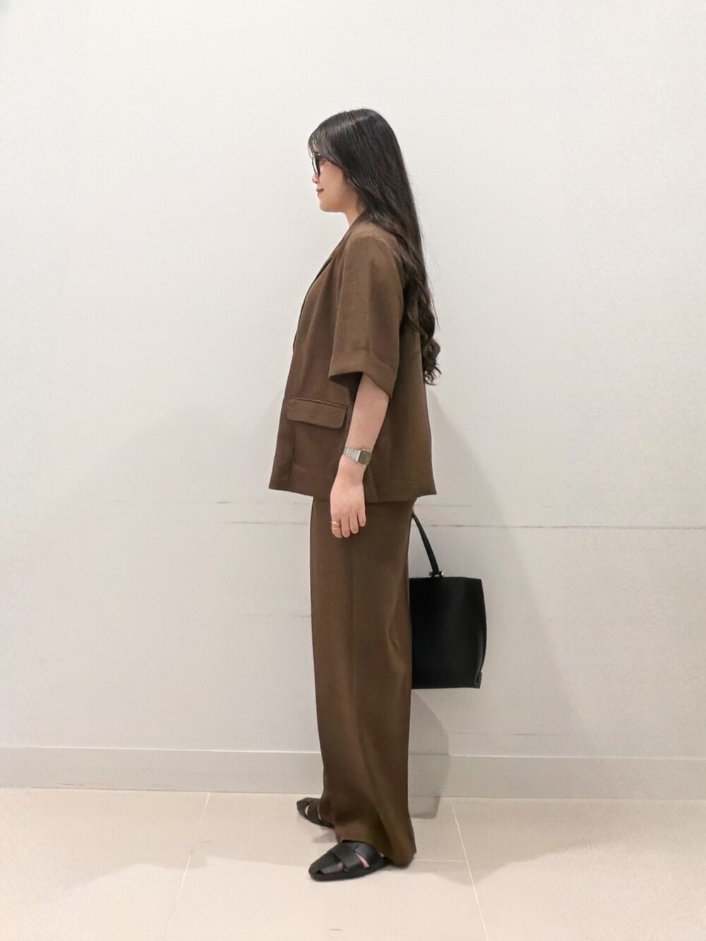 ブラウン系のその他パンツ、ブラック系のサンダル、ブラック系のビジネスバッグを着用したレディースの夏コーディネートの5枚目の写真