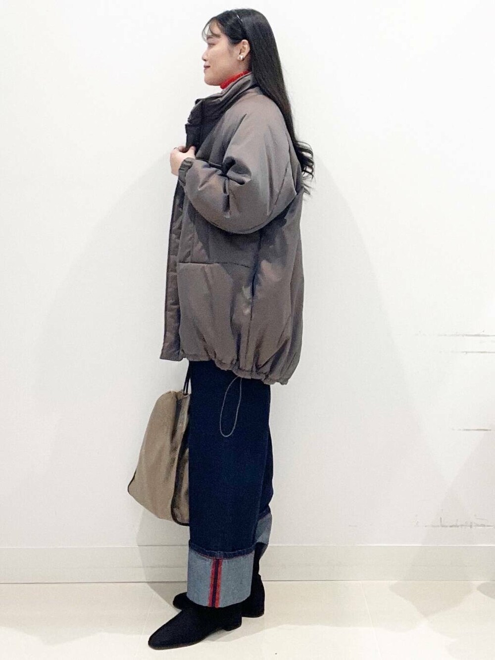 ブラック系のブーツ、レッド系のニット/セーター、ブルー系のデニムパンツを着用したレディースの冬コーディネートの5枚目の写真