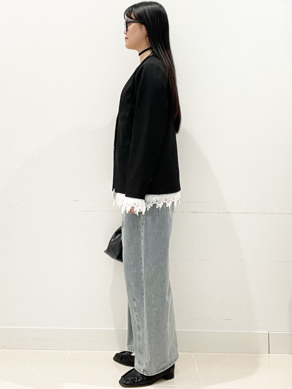 ブラック系のローファー、ブルー系のデニムパンツ、ブラック系のハンドバッグを着用したレディースの春コーディネートの5枚目の写真