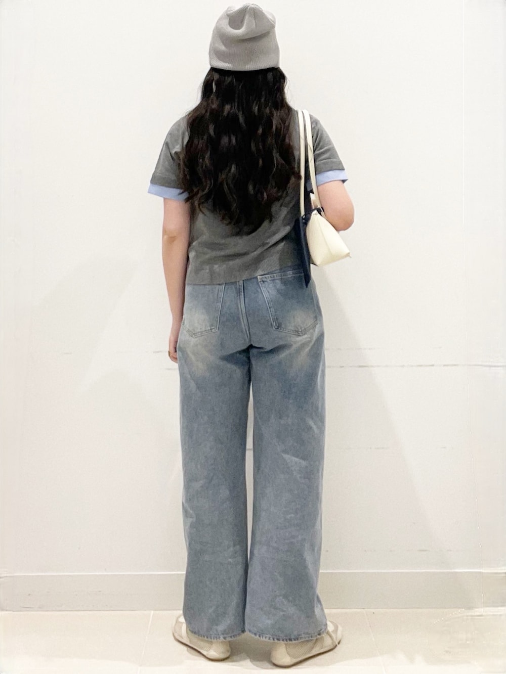 ブルー系のデニムパンツ、グレー系のカーディガン/ボレロ、ホワイト系のショルダーバッグを着用したレディースの春コーディネートの5枚目の写真