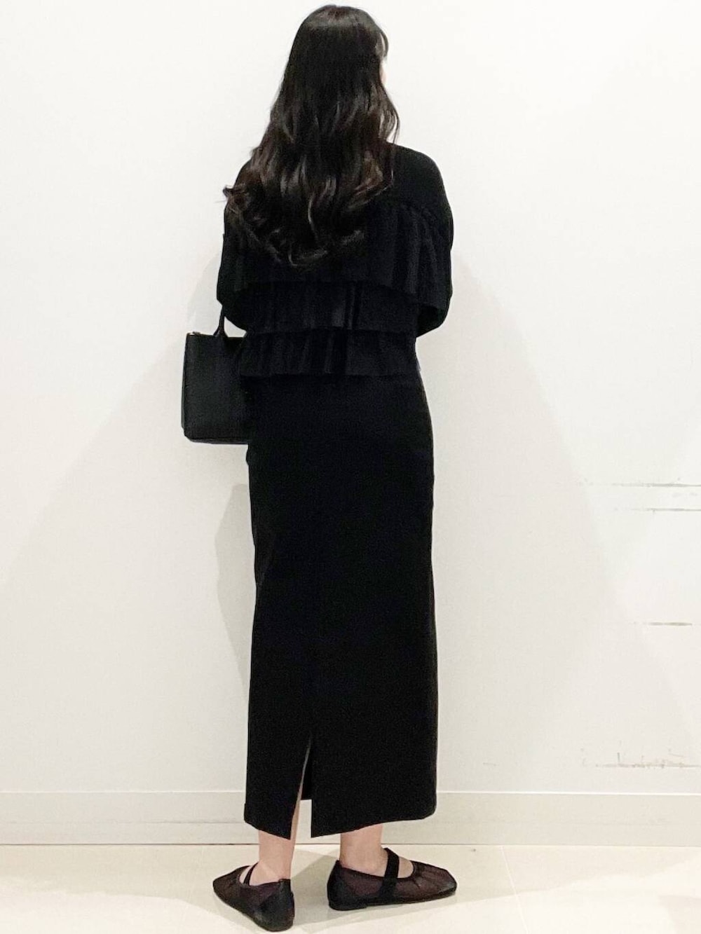 ブラック系のニット/セーター、ブラック系のスカート、ブラック系のトートバッグを着用したレディースの春コーディネートの5枚目の写真