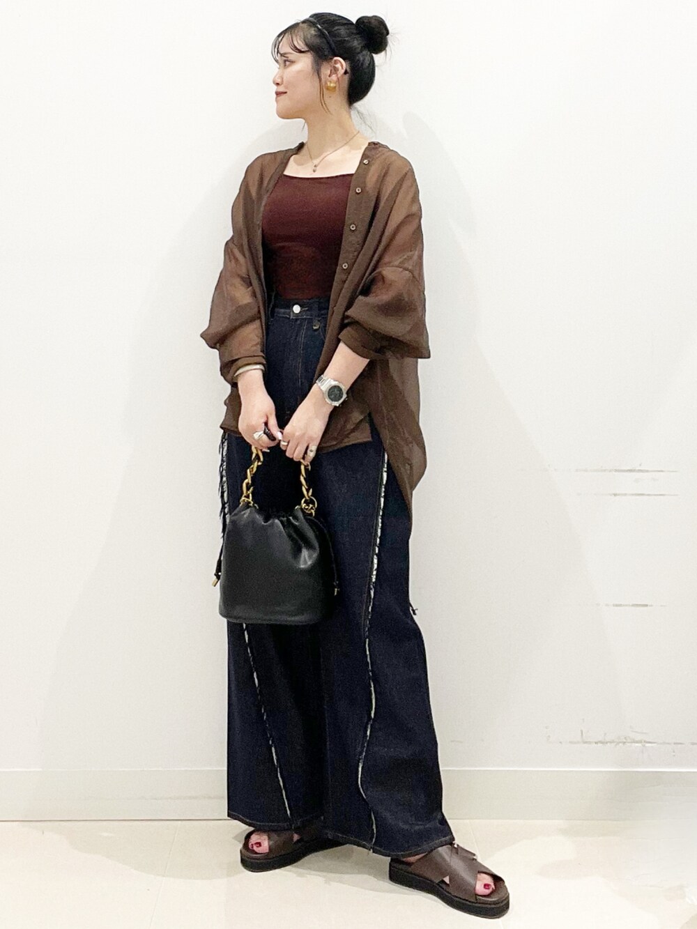 ブラウン系のサンダル、ブルー系のデニムパンツ、ブラック系のショルダーバッグを着用したレディースの夏コーディネートの2枚目の写真