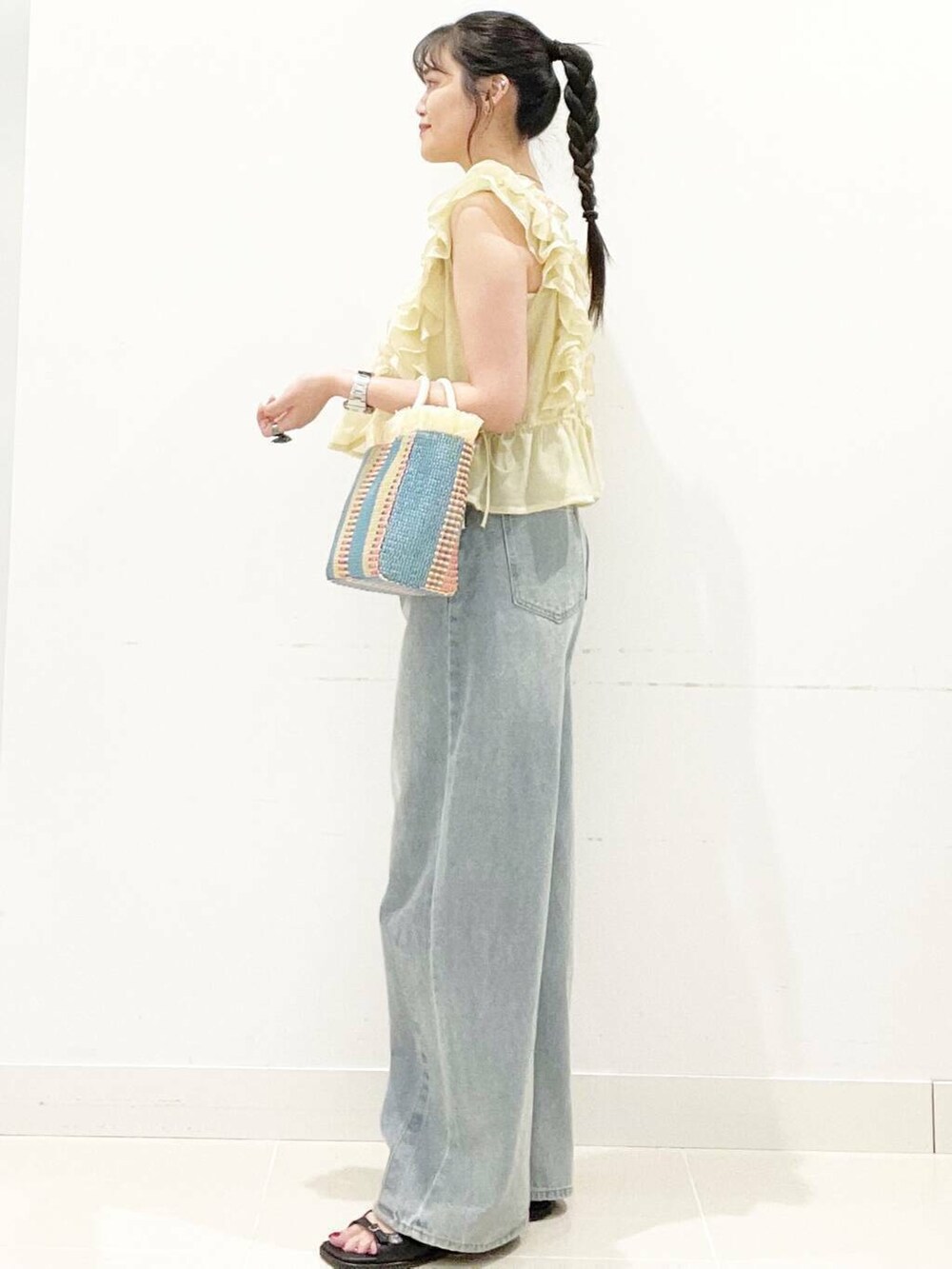 ホワイト系のキャミソール、ブルー系のデニムパンツ、ベージュ系のショルダーバッグを着用したレディースの夏コーディネートの4枚目の写真