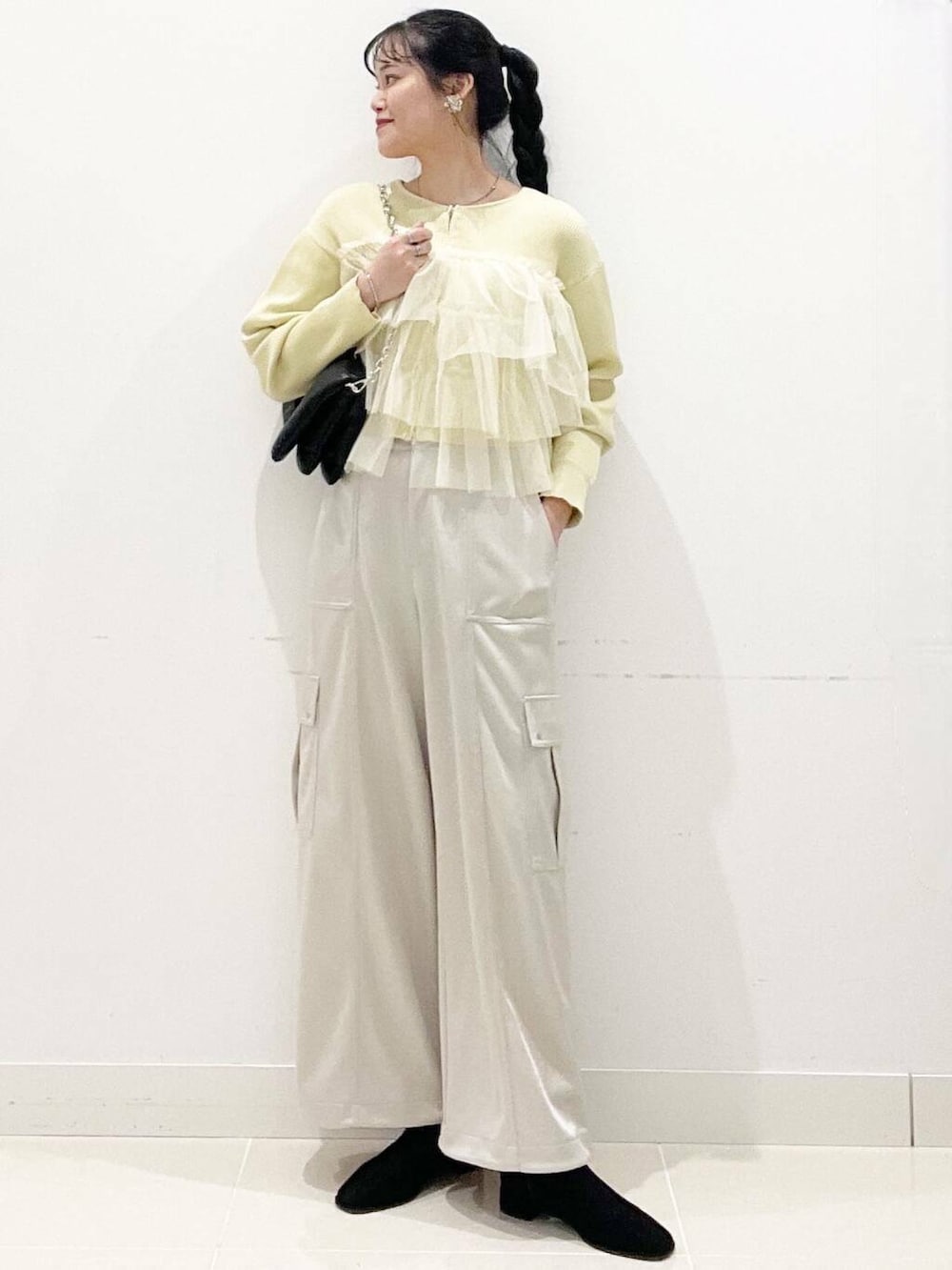 ブラック系のブーツ、ブラック系のショルダーバッグ、イエロー系のニット/セーターを着用したレディースの冬コーディネートの3枚目の写真