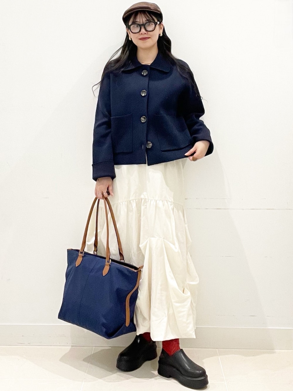 ブラック系のその他シューズ、ホワイト系のスカート、ブルー系のビジネスバッグを着用したレディースの冬コーディネートの2枚目の写真