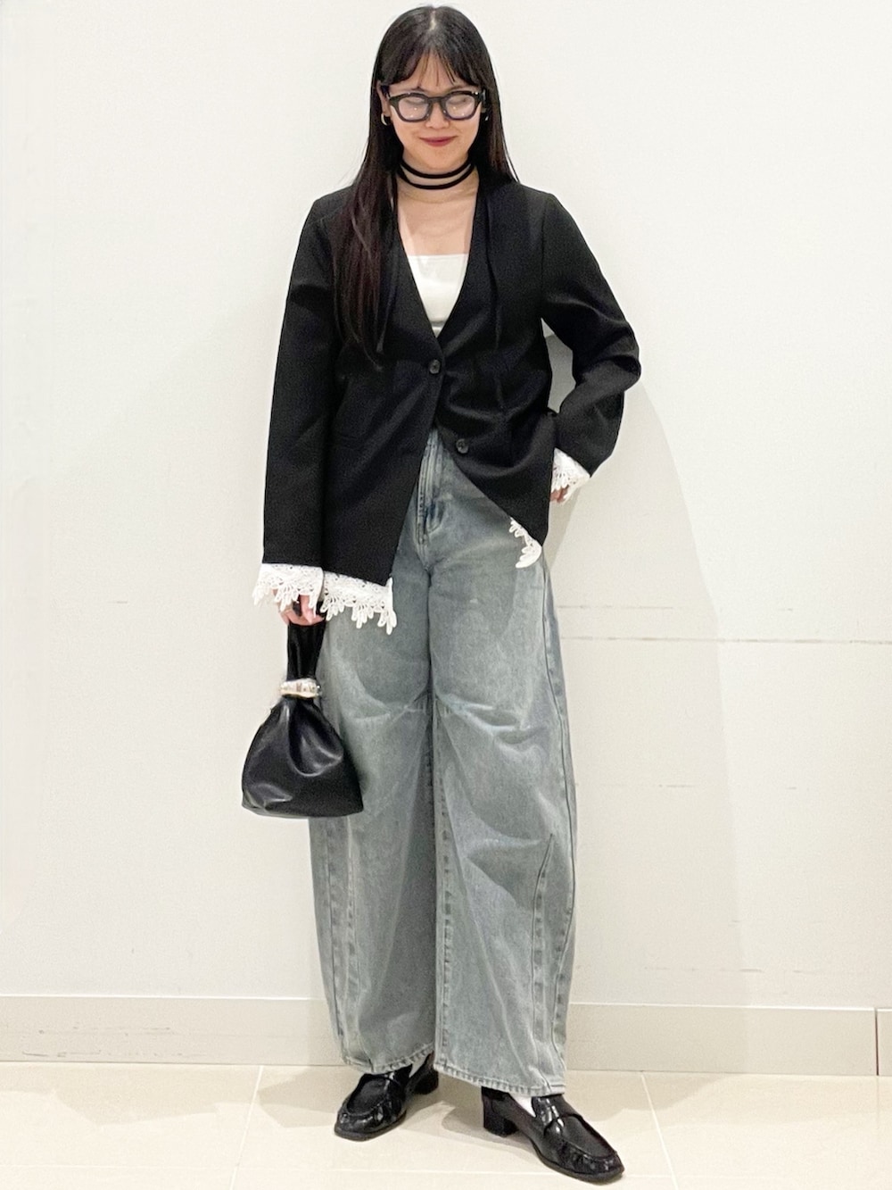 ブラック系のローファー、ブルー系のデニムパンツ、ブラック系のハンドバッグを着用したレディースの春コーディネートの4枚目の写真