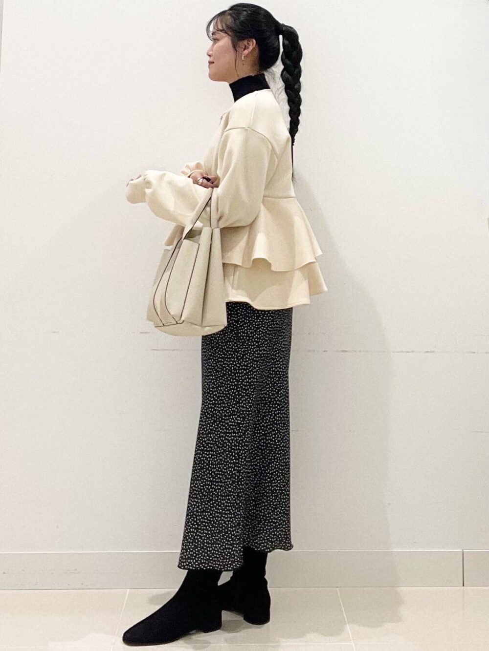 ブラック系のニット/セーター、ブラック系のブーツ、ホワイト系のトートバッグを着用したレディースの冬コーディネートの5枚目の写真