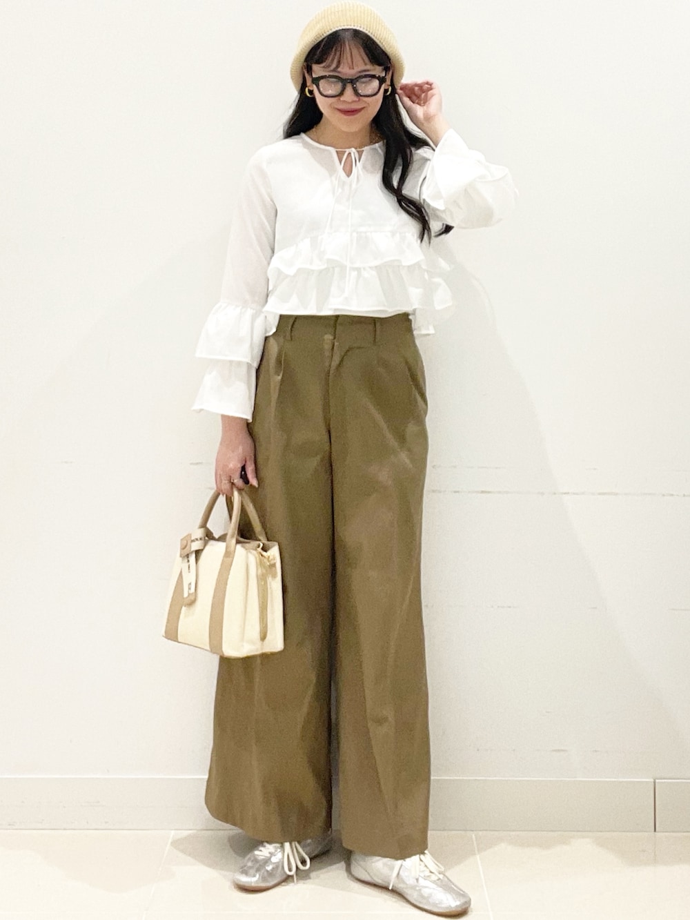 ベージュ系のチノパンツ、ホワイト系のハンドバッグ、ホワイト系のキャミソールを着用したレディースの春コーディネートの4枚目の写真