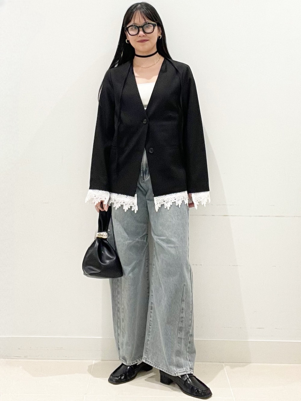 ブラック系のローファー、ブルー系のデニムパンツ、ブラック系のハンドバッグを着用したレディースの春コーディネートの2枚目の写真