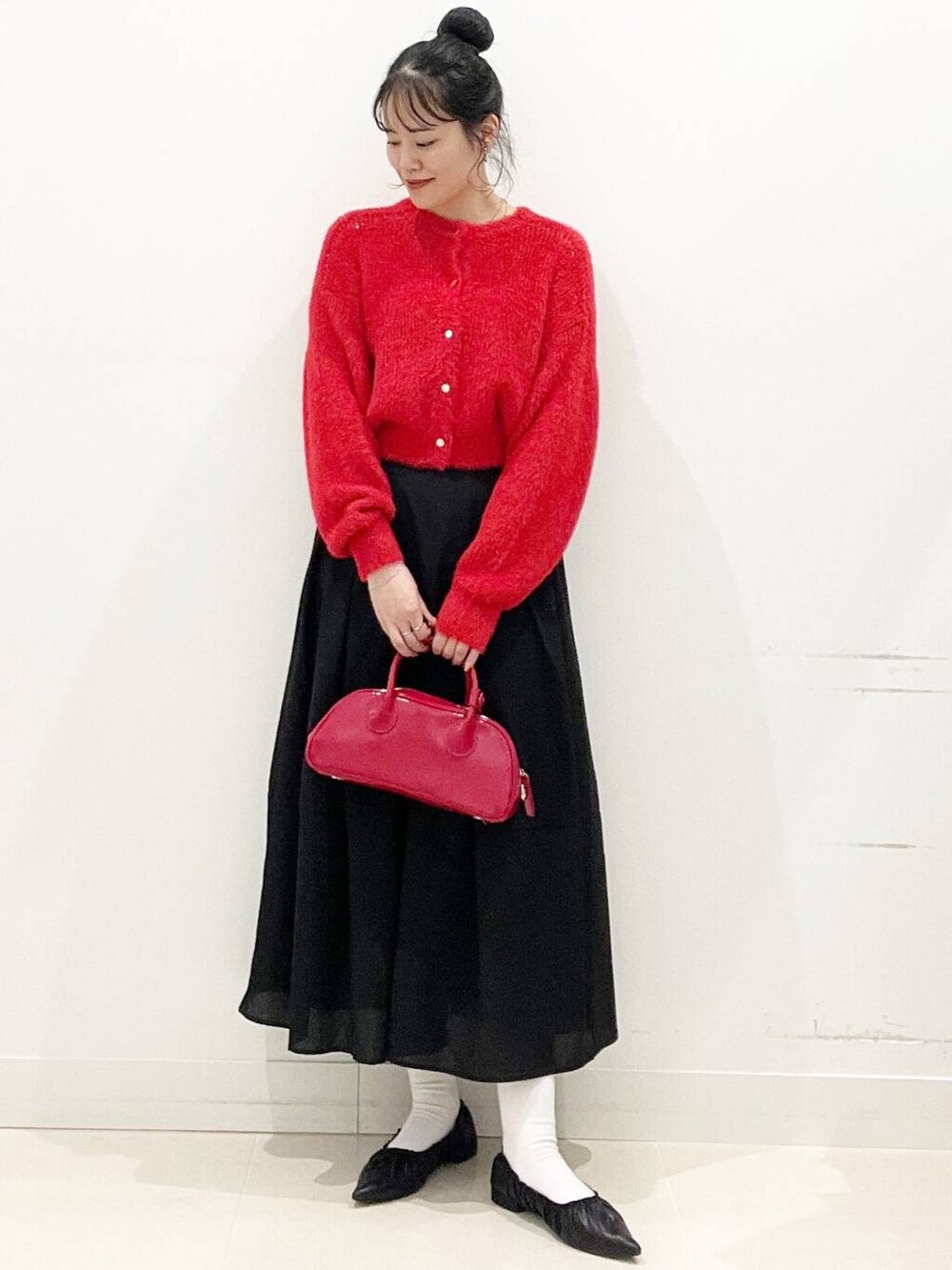 レッド系のボストンバッグ、レッド系のニット/セーター、ブラック系のバレエシューズを着用したレディースの冬コーディネートの5枚目の写真