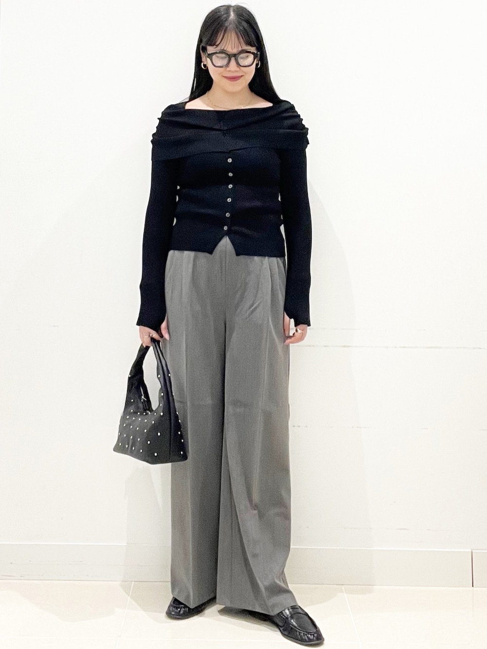 グレー系のスラックス、ブラック系のハンドバッグ、ブラック系のニット/セーターを着用したレディースの春コーディネートの4枚目の写真