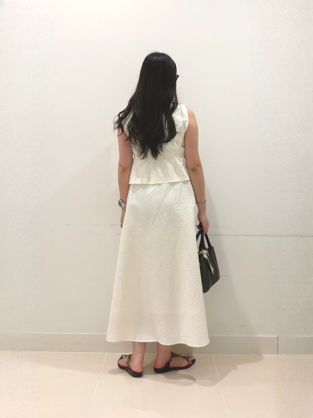 ホワイト系のワンピース、ブラック系のハンドバッグ、ブラック系のサンダルを着用したレディースの夏コーディネートの4枚目の写真