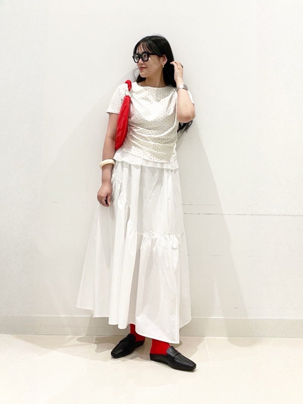 ホワイト系のスカート、ホワイト系のTシャツ/カットソー、レッド系のハンドバッグを着用したレディースの春コーディネートの2枚目の写真