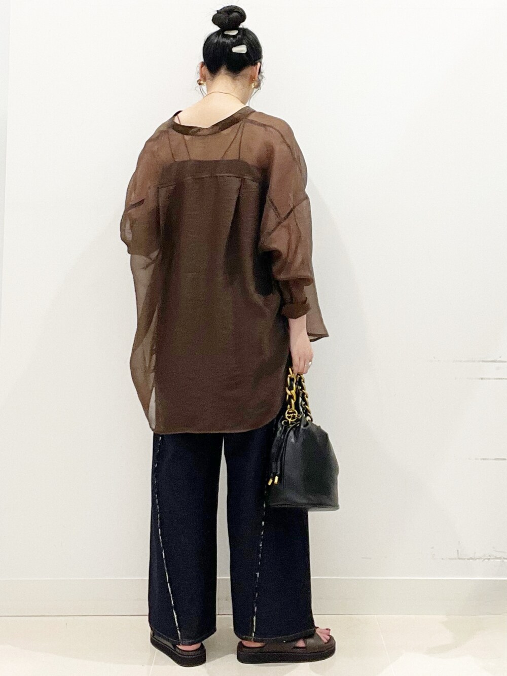 ブラウン系のサンダル、ブルー系のデニムパンツ、ブラック系のショルダーバッグを着用したレディースの夏コーディネートの5枚目の写真