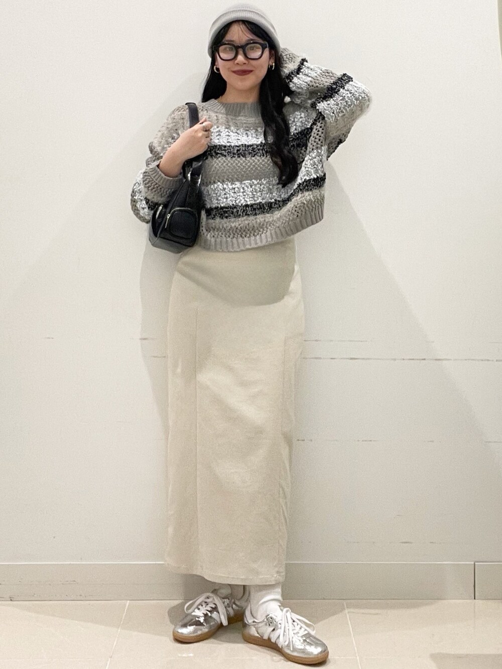 シルバー系のスニーカー、ベージュ系のスカート、グレー系のニット/セーターを着用したレディースの春コーディネートの2枚目の写真