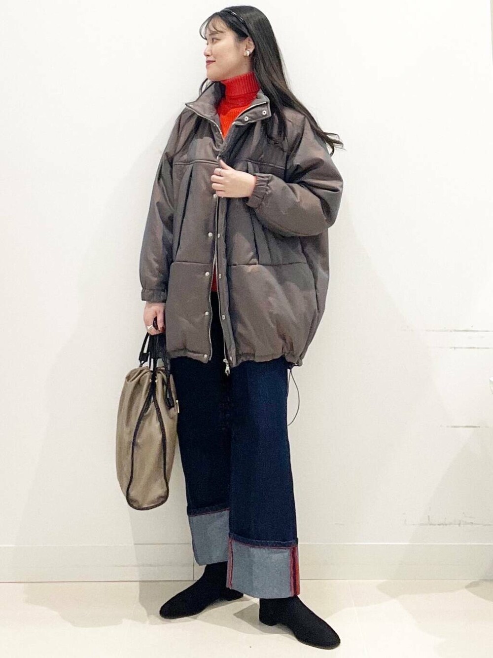 ブラック系のブーツ、レッド系のニット/セーター、ブルー系のデニムパンツを着用したレディースの冬コーディネートの2枚目の写真