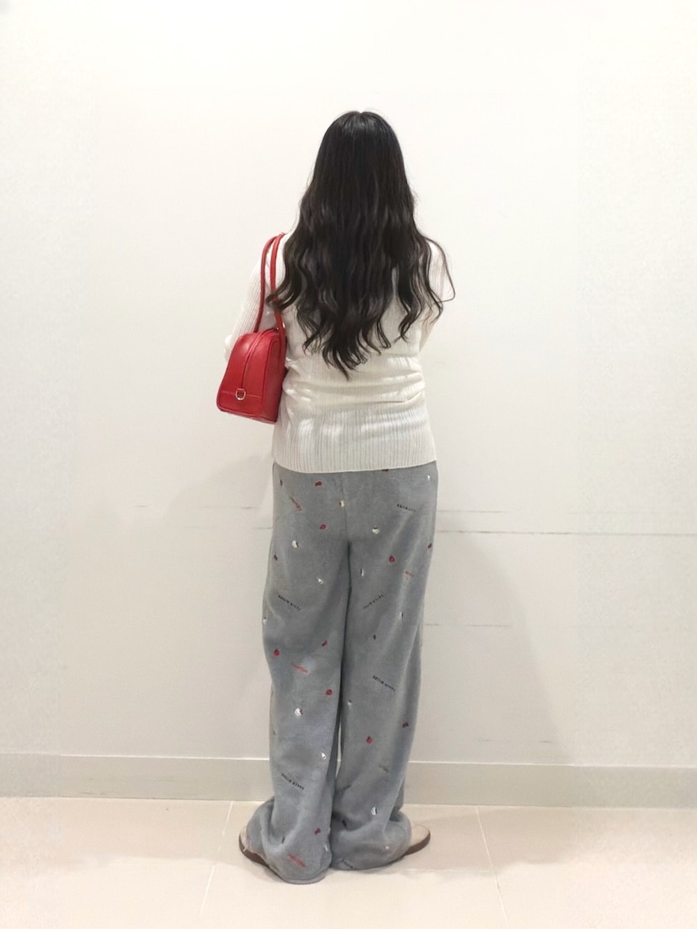 ホワイト系のニット/セーター、グレー系のその他パンツ、レッド系のボストンバッグを着用したレディースの秋コーディネートの5枚目の写真