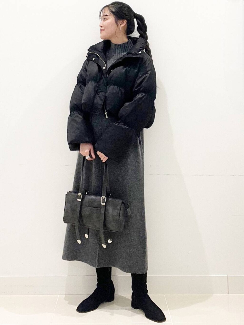 ブラック系のダウンジャケット/コート、ブラック系のブーツ、グレー系のワンピースを着用したレディースの冬コーディネートの2枚目の写真