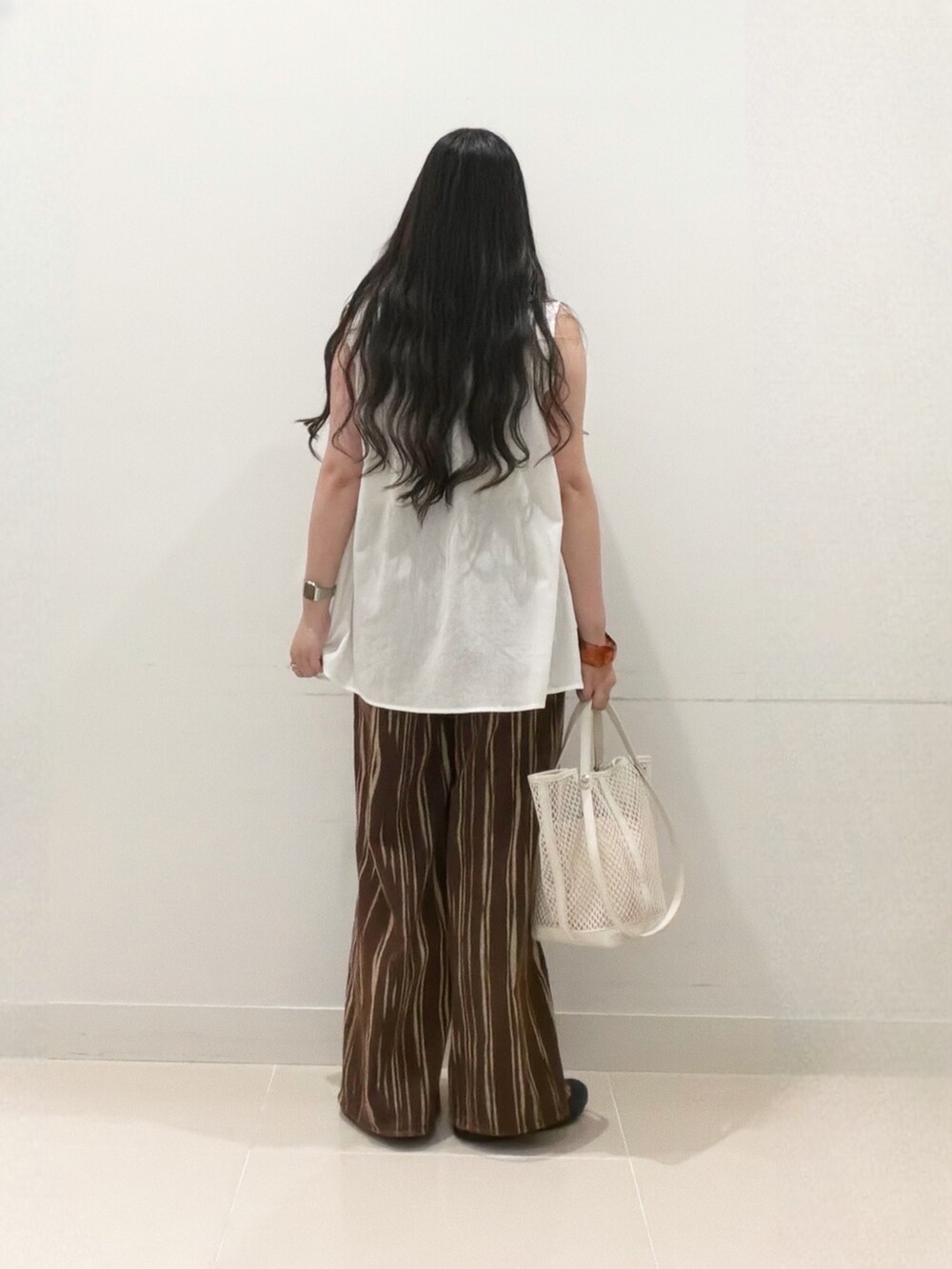 ブラウン系のデニムパンツ、ホワイト系のトートバッグ、ブラック系のサンダルを着用したレディースの夏コーディネートの5枚目の写真