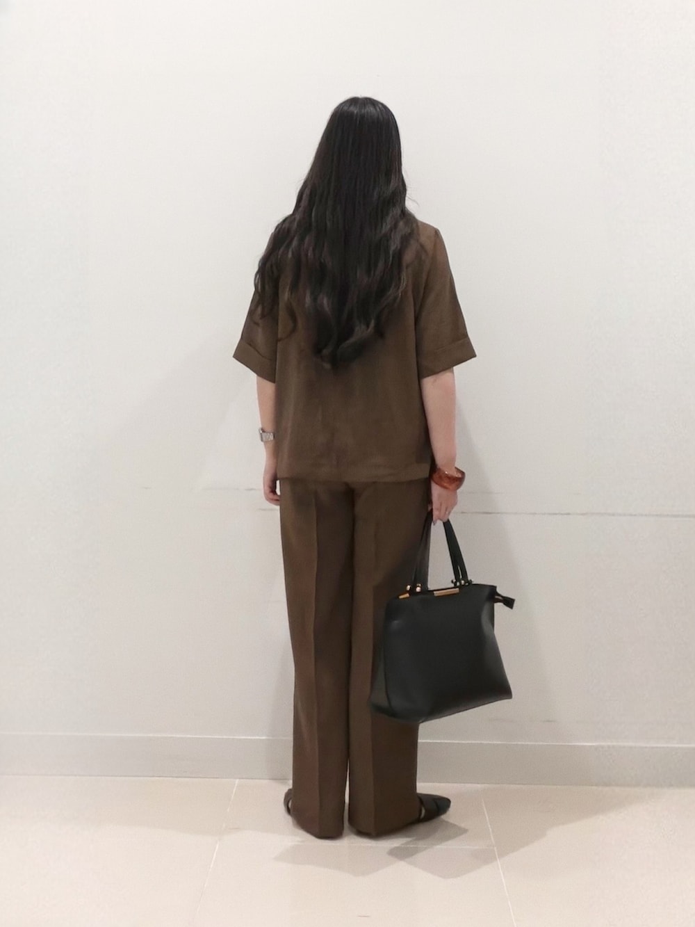 ブラウン系のその他パンツ、ブラック系のサンダル、ブラック系のビジネスバッグを着用したレディースの夏コーディネートの6枚目の写真