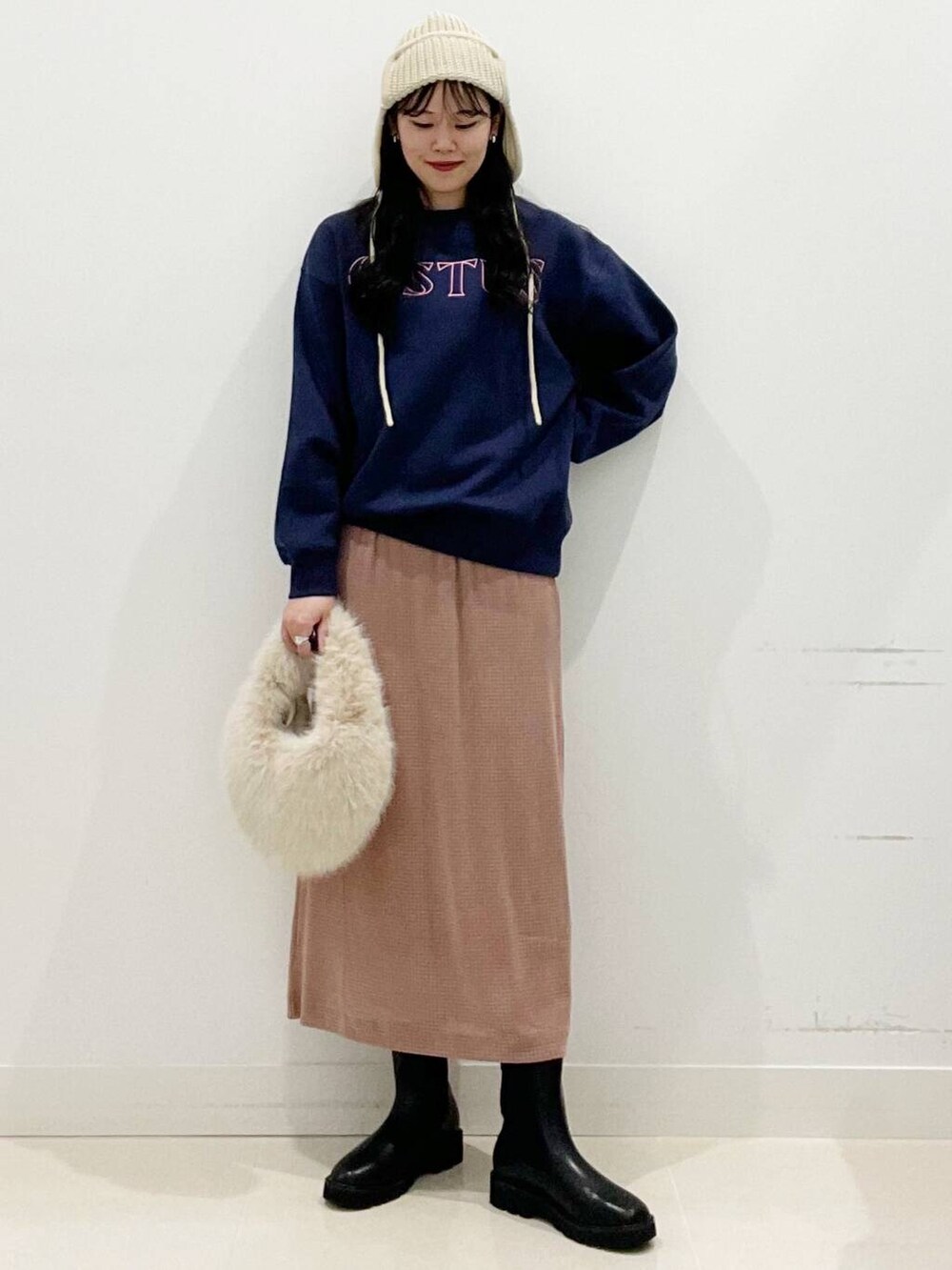 ベージュ系のハンドバッグ、ブラック系のブーツ、ピンク系のスカートを着用したレディースの秋コーディネートの5枚目の写真