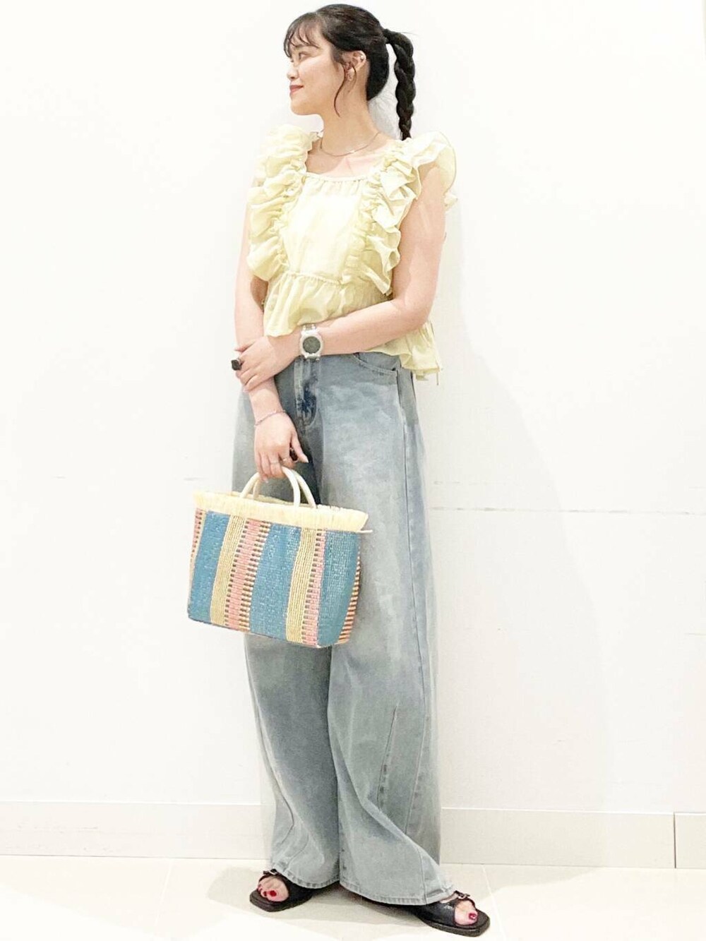 ホワイト系のキャミソール、ブルー系のデニムパンツ、ベージュ系のショルダーバッグを着用したレディースの夏コーディネートの3枚目の写真