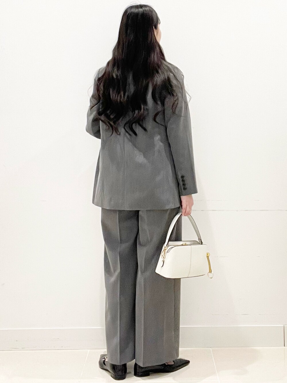 ブラック系のパンプス、グレー系のスラックス、ホワイト系のハンドバッグを着用したレディースの冬コーディネートの6枚目の写真