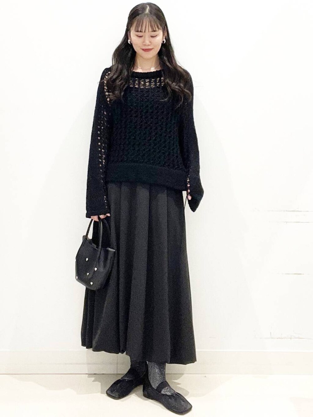 ブラック系のショルダーバッグ、ブラック系のスカート、ブラック系のニット/セーターを着用したレディースの春コーディネートの3枚目の写真