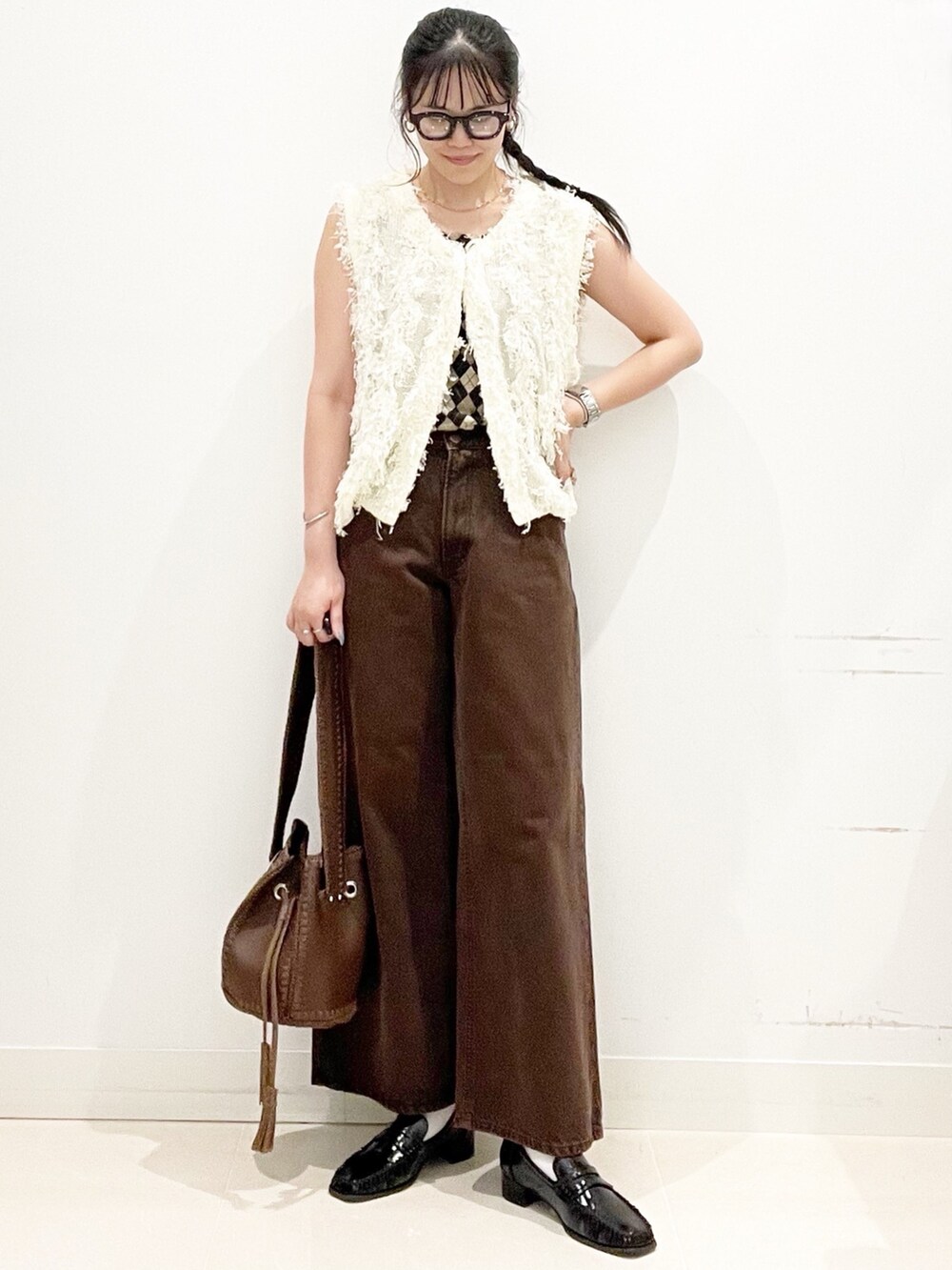 ブラック系のローファー、ブラウン系のショルダーバッグ、ブラウン系のデニムパンツを着用したレディースの夏コーディネートの4枚目の写真